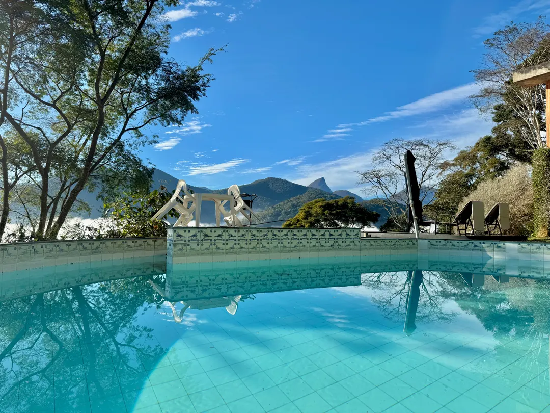 Piscina privativa do Refúgio Céu Azul em dia claro, com neblina leve nas montanhas ao fundo