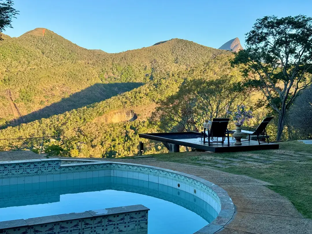 Piscina do Refúgio Céu Azul ao entardecer, com o céu colorido sobre as montanhas