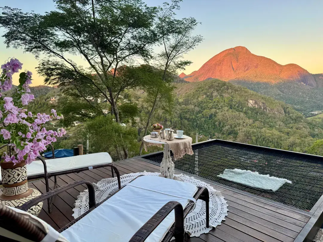 Deck do Refúgio Céu Azul com espreguiçadeiras, mesa decorada e vista para a serra ao entardecer