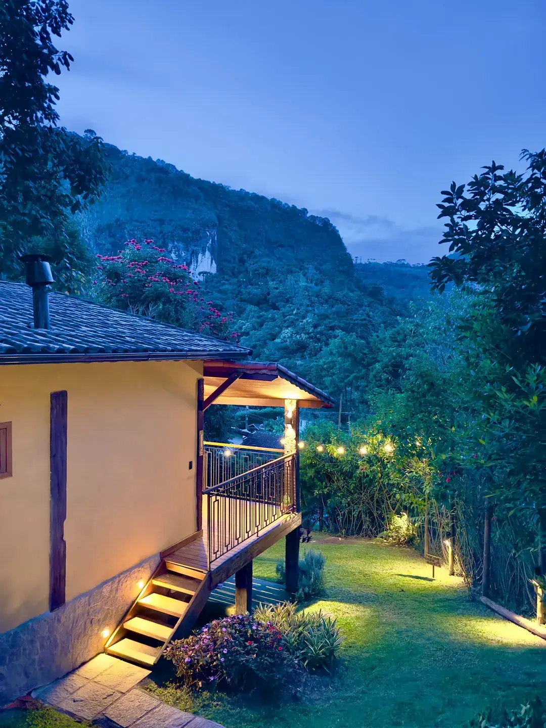 Chalé Lua Nova ao entardecer, com a serra ao fundo e o deck iluminado