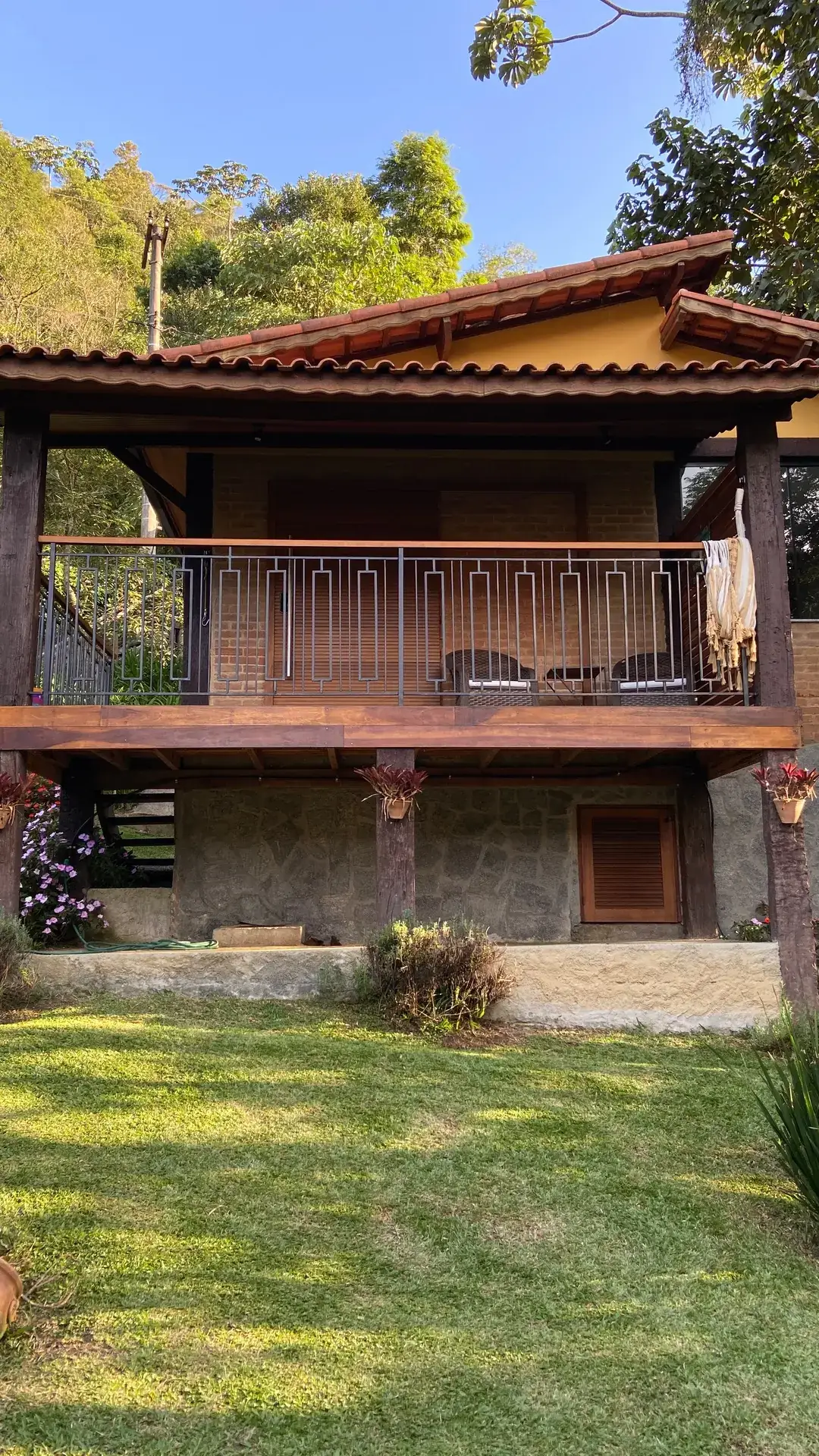 Varanda superior do Chalé Lua Nova ao entardecer, com vista para o jardim e a serra