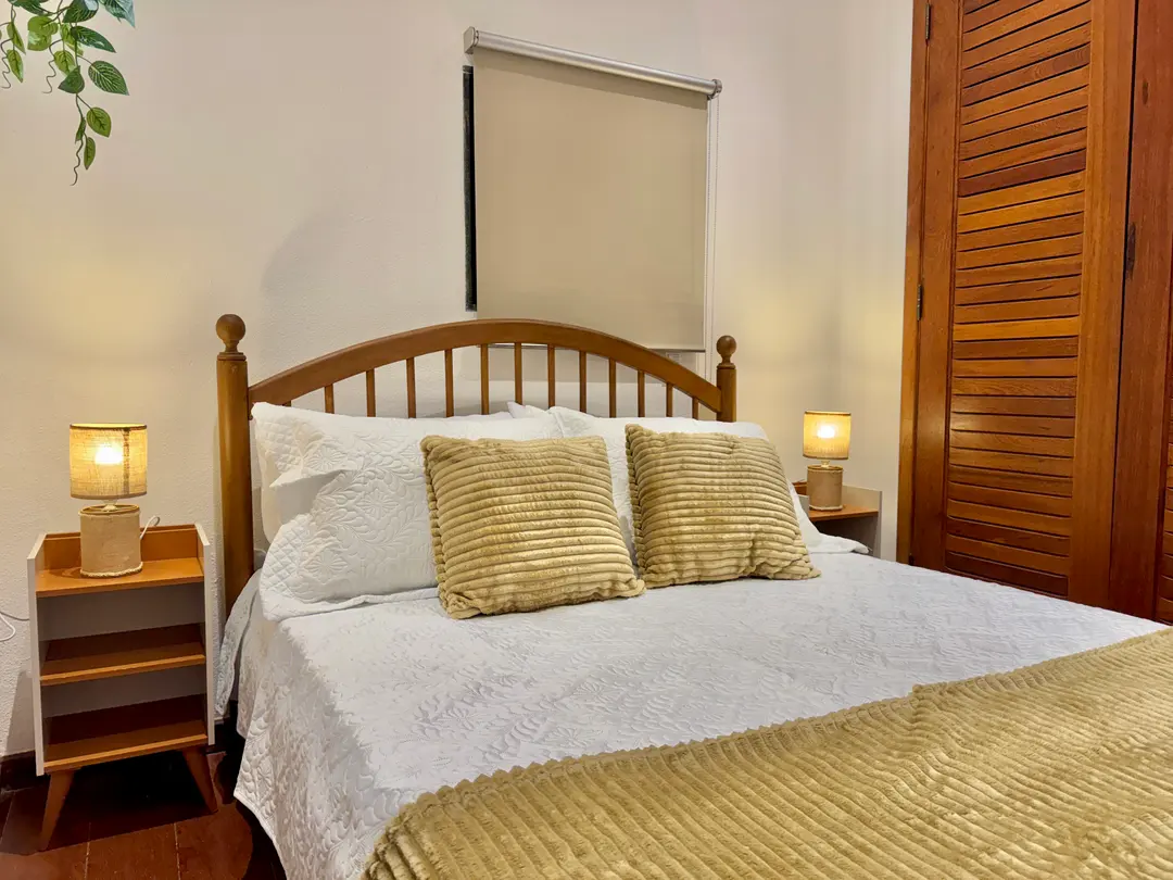 Quarto de casal da Cabana Orion com cabeceira de madeira torneada e roupa de cama clara