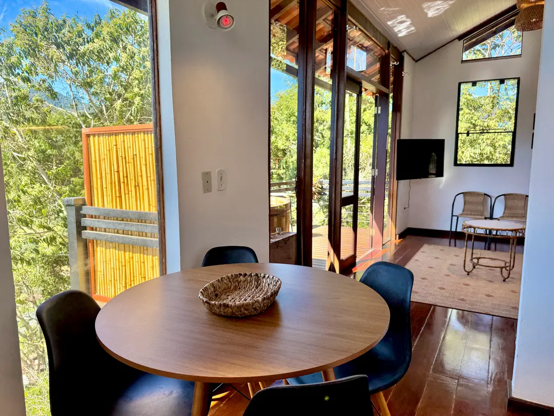 Mesa de jantar da Cabana Orion com a tela de bambu do ofurô visível pela porta de vidro
