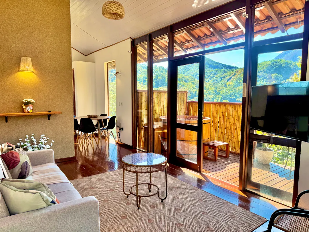 Sala de estar da Cabana Orion com sofá e portas de vidro abertas para o deck