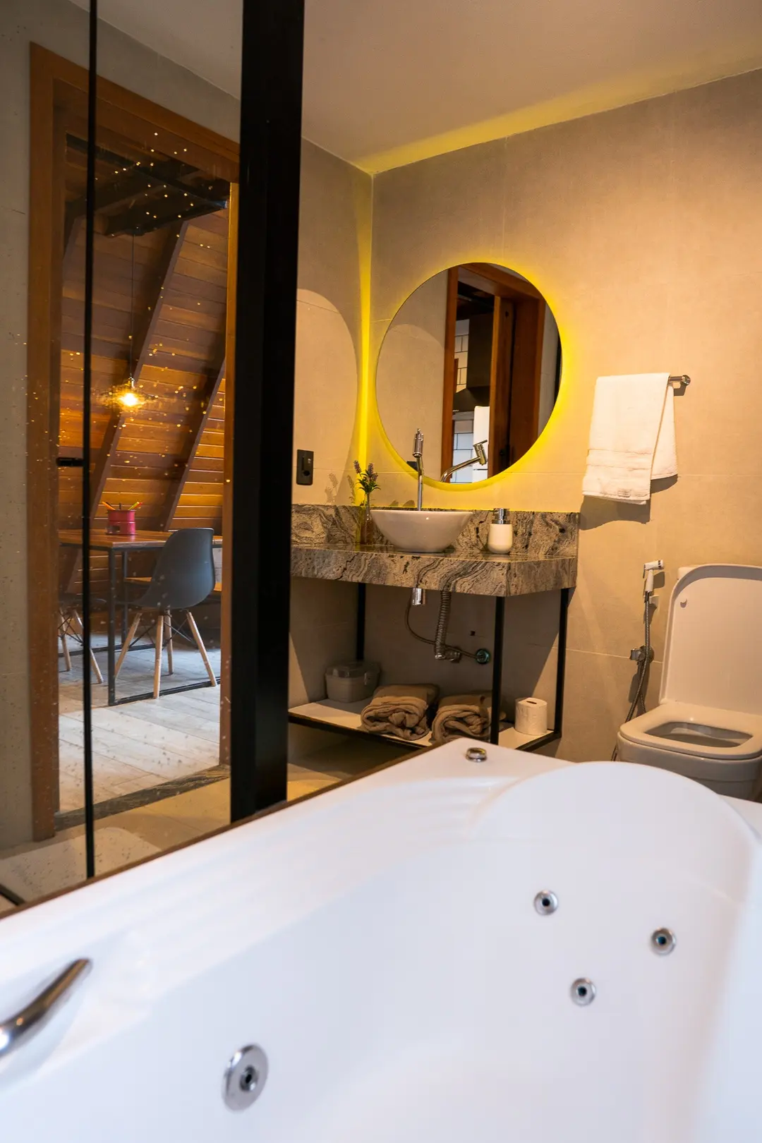 Banheiro da Sirius com hidromassagem dupla vista da porta, pia e espelho redondo