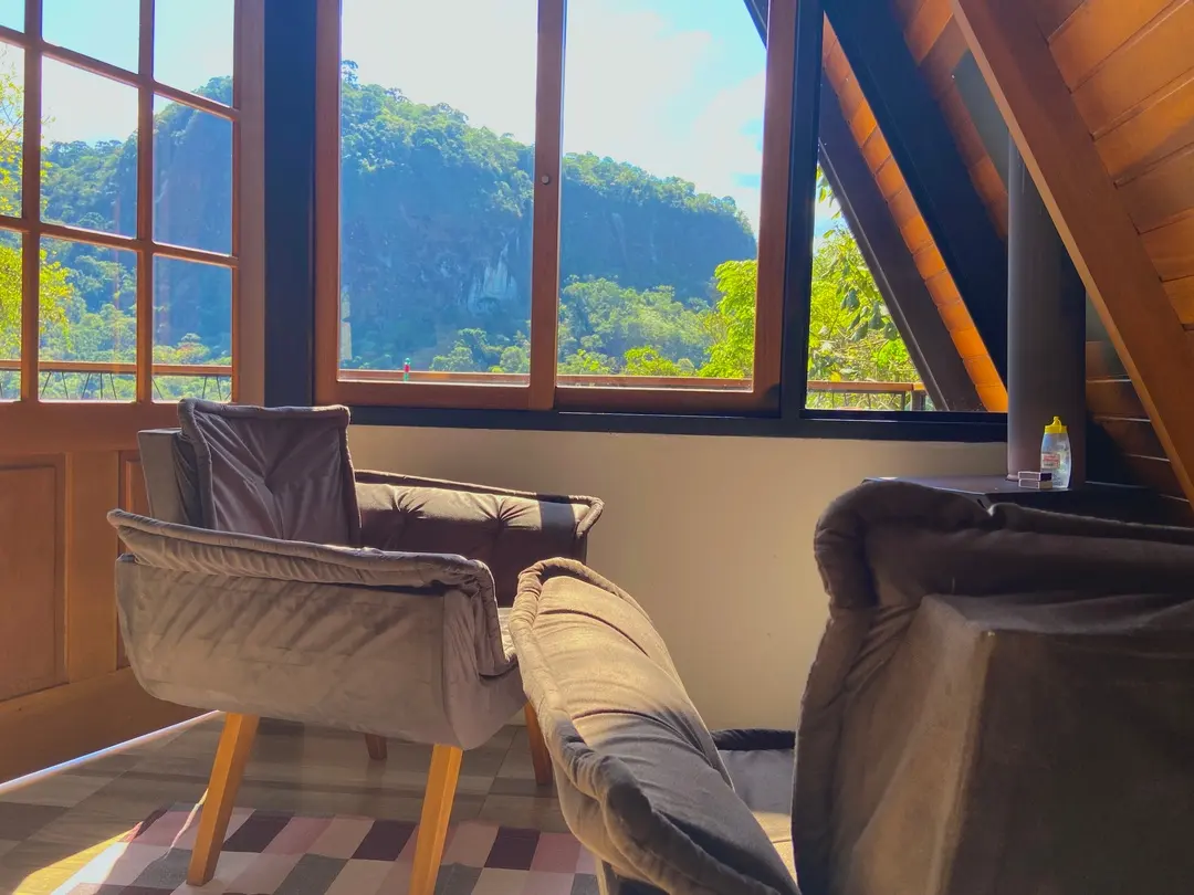 Poltronas na sala da Cabana Sirius com janela emoldurando a montanha ao fundo