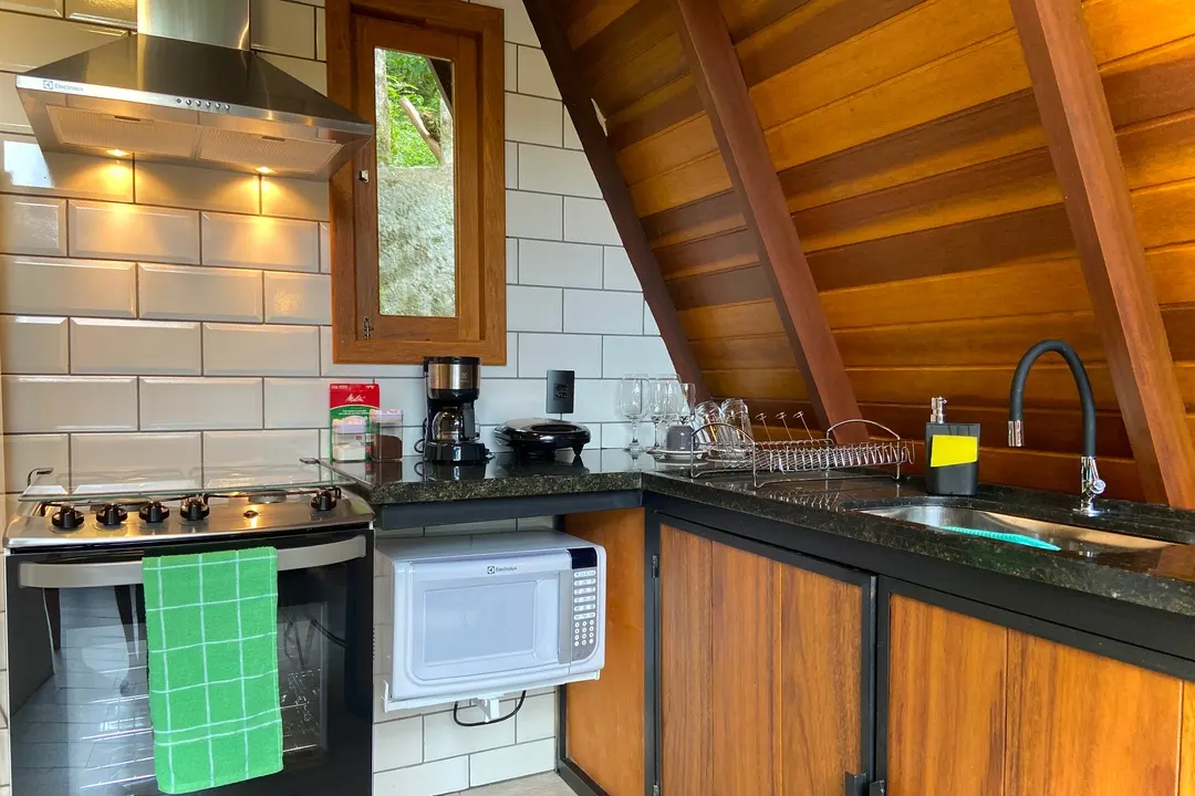 Cozinha completa da Sirius com fogão, forno e micro-ondas embutidos em marcenaria de madeira
