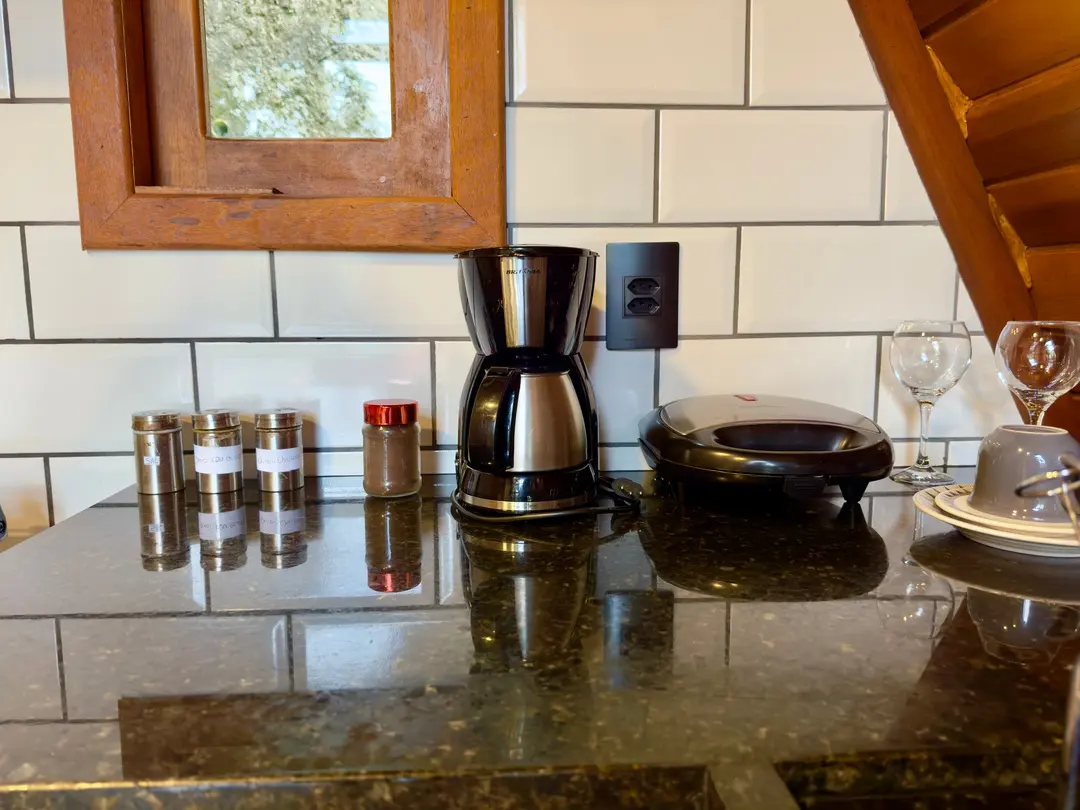 Bancada de granito com cafeteira, potes de tempero e taça, revestimento de subway tile