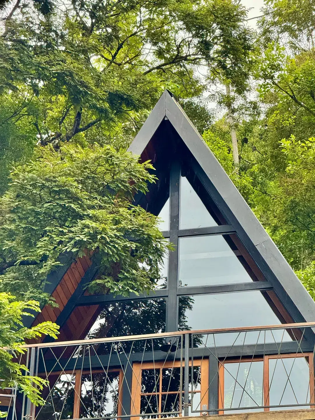 Placa de madeira com o nome Cabanas Sirius e Solaris na entrada, cabana ao fundo entre as árvores