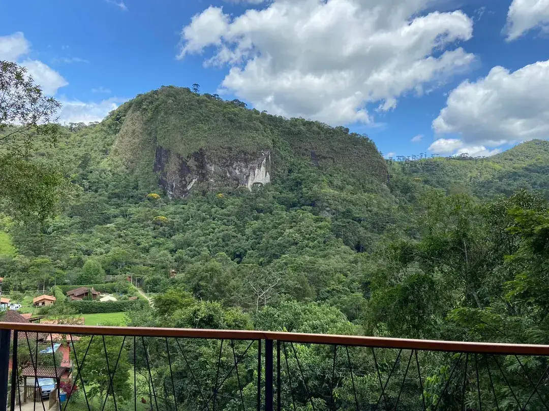 Vista de uma montanha coberta de mata a partir da varanda da Cabana Sirius