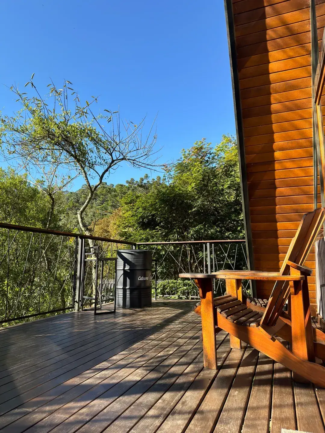 Deck da Cabana Solaris pela manhã, com sol na madeira e o verde do vale ao fundo