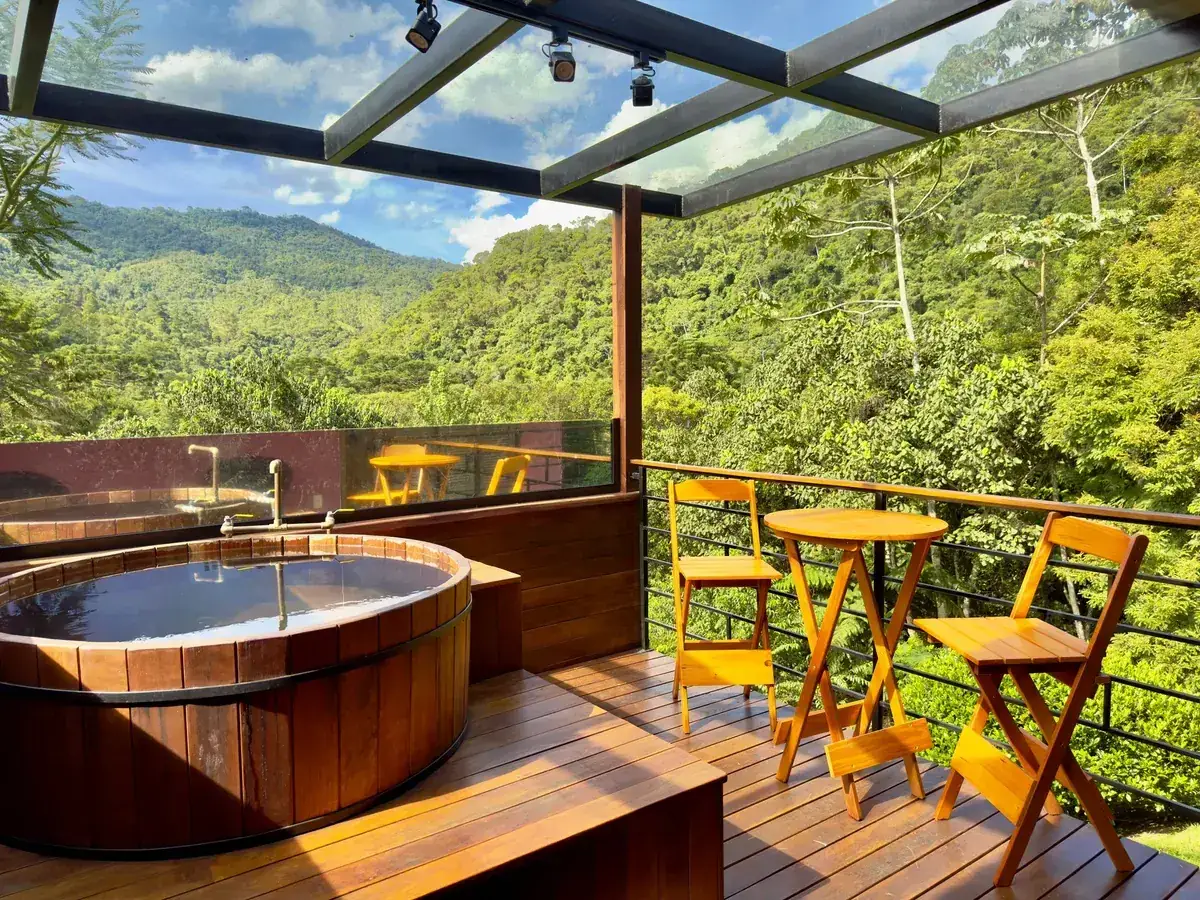 Ofurô de madeira no deck coberto de vidro do Studio Lua Nova, com vista para a serra