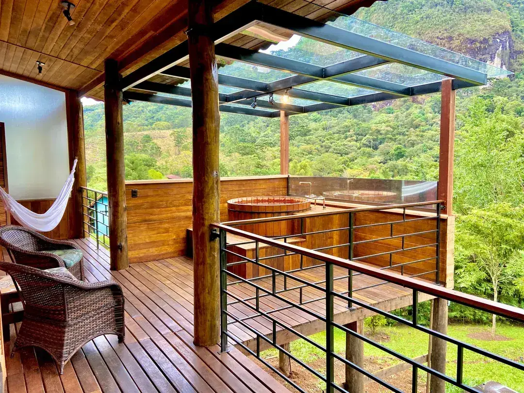 Deck coberto de vidro do Studio com poltronas de vime e o ofurô ao fundo