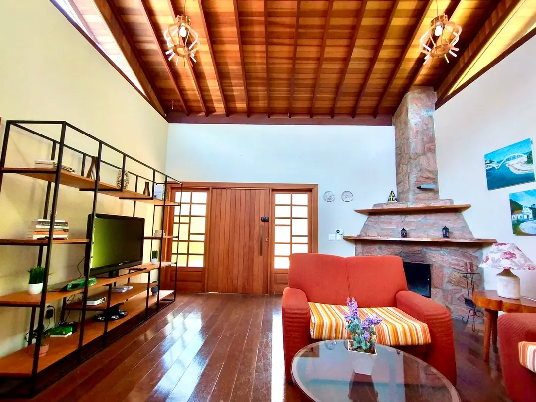 Sala de estar do Studio Lua Nova com lareira interna e poltrona vermelha