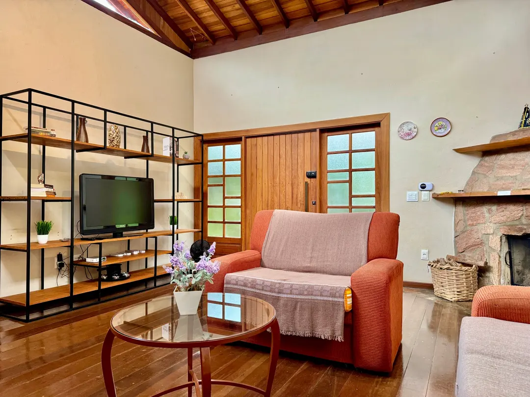 Sala de estar com sofá laranja, estante e TV