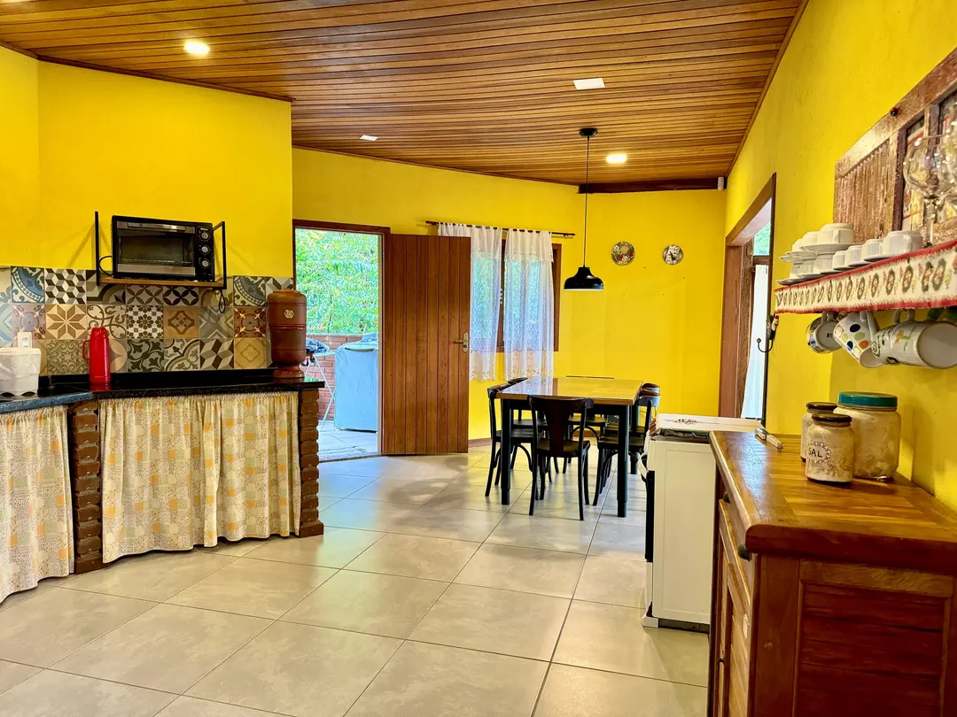 Cozinha equipada do Studio, com parede amarela e piso de porcelanato