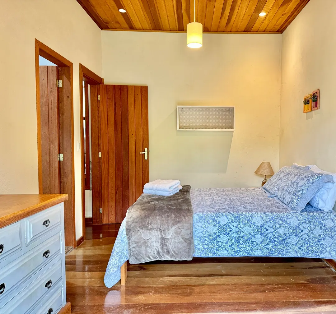 Suíte do Studio Lua Nova com cama de casal e cômoda de madeira